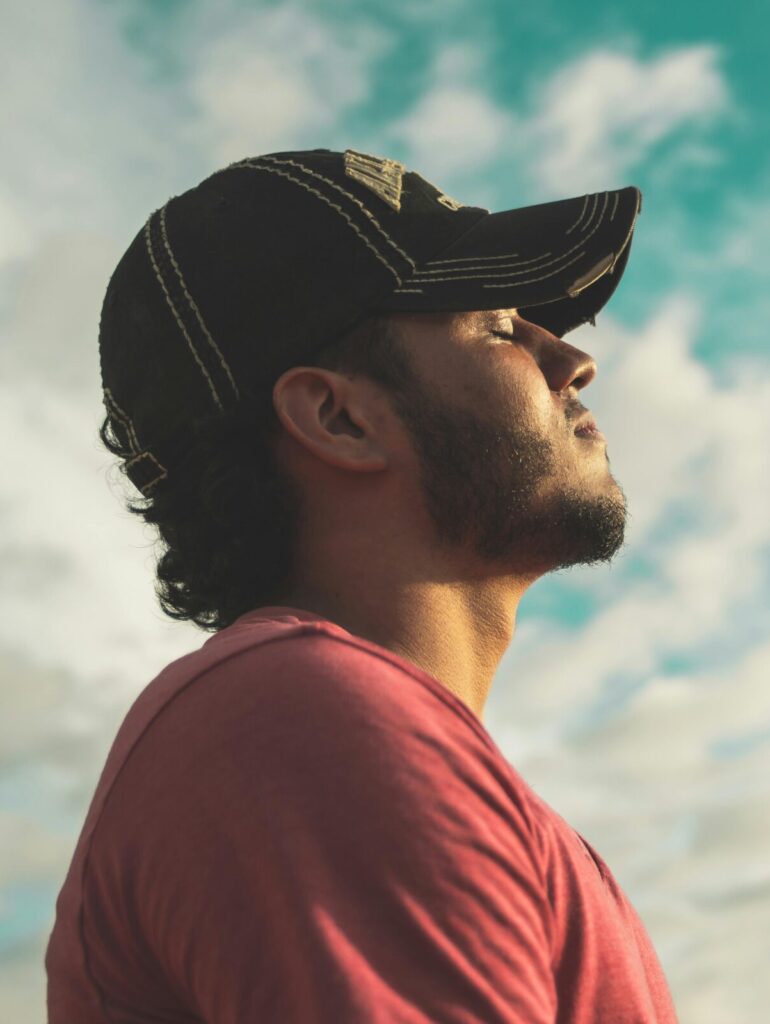 A man enjoys outdoor relaxation and mindfulness beneath a bright, cloudy sky, exuding calm and peace.